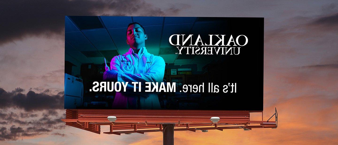 A billboard featuring a young man and the words "Oakland University. It's all here. Make it Yours."